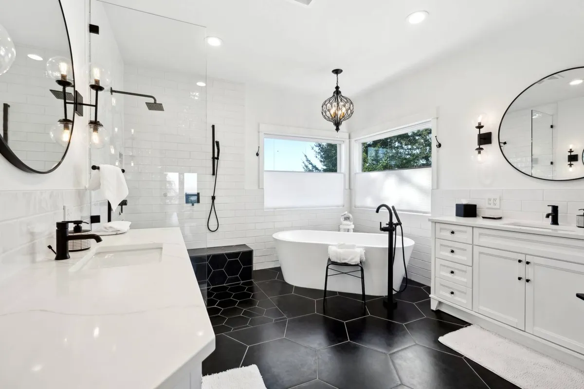 A calming bathroom scene featuring a freestanding bathtub beside a large window, hexagonal tile flooring, and accent lighting. The setting evokes a sense of rejuvenation and self-care.
