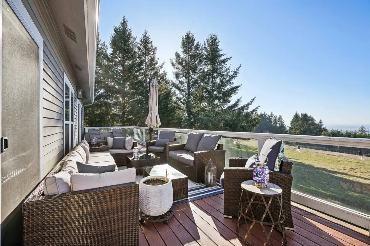 A cozy outdoor seating area is arranged under an umbrella with a decorative lantern providing gentle light. Comfortable chairs invite guests to relax, sip their morning coffee, or enjoy peaceful evenings, with a sense of openness to the surrounding landscape.