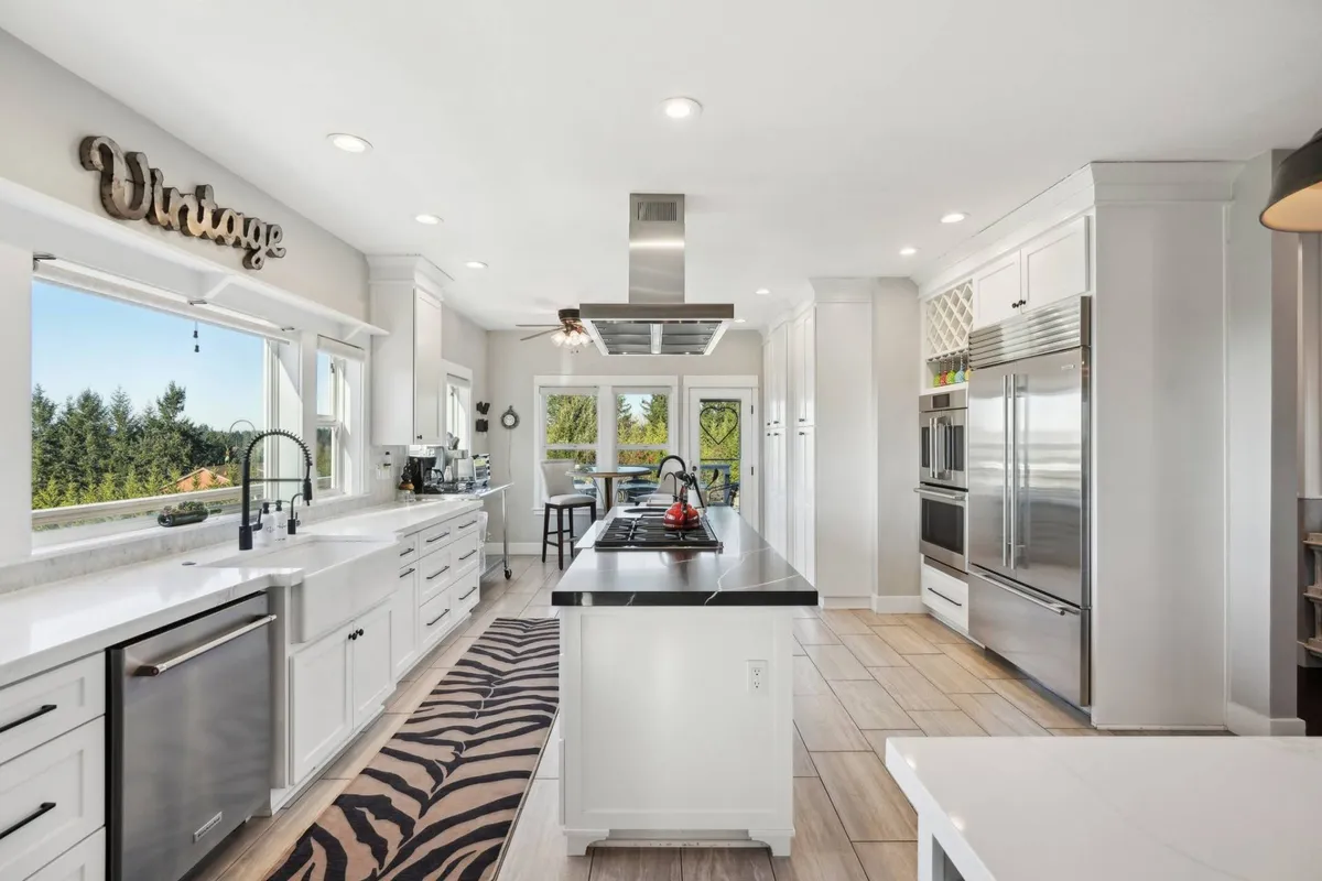 A modern kitchen space with a large island, stainless steel appliances, a vintage sign, and a zebra print rug. The layout is ideal for cooking and entertaining, providing ample space for preparing snacks or late-night treats.