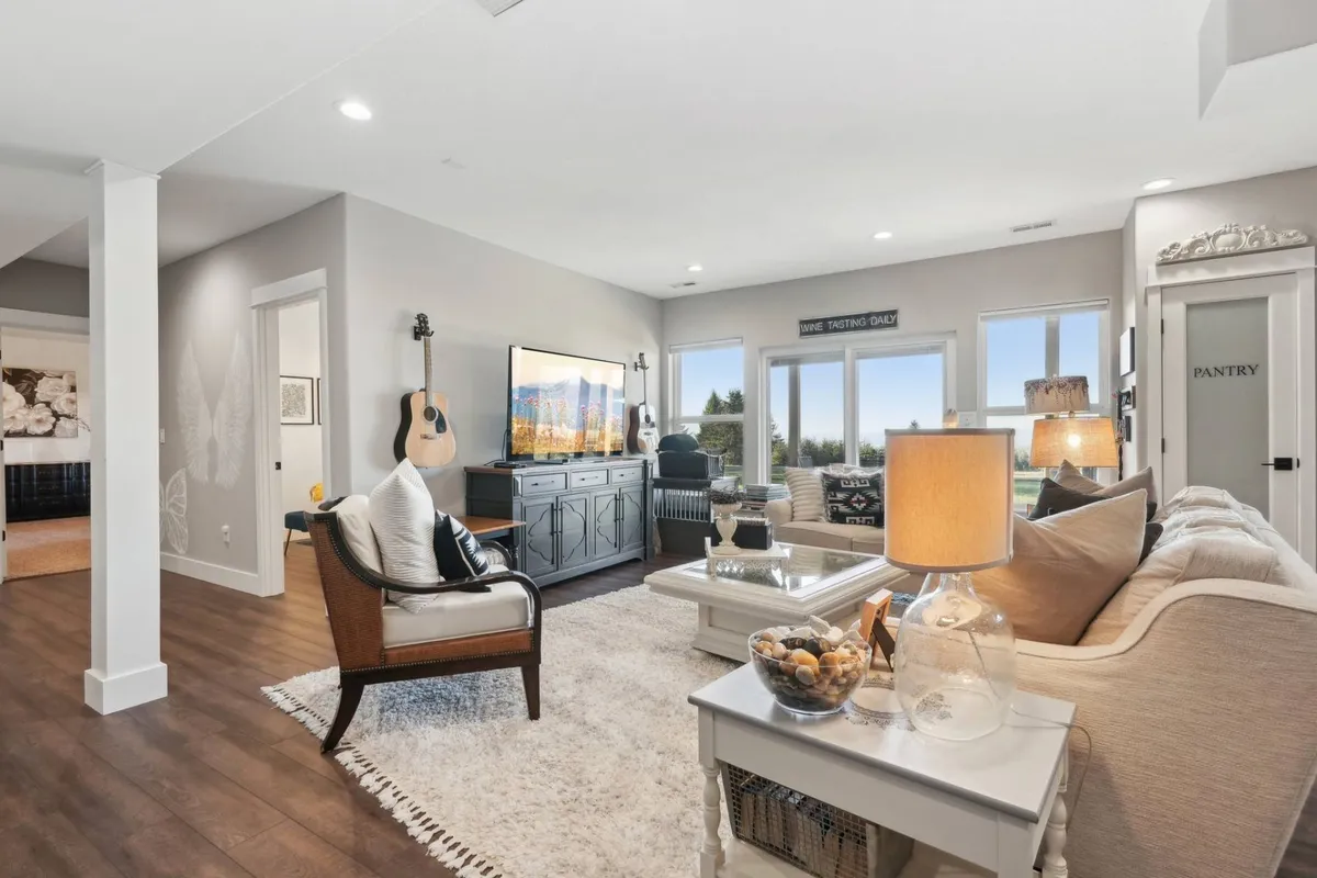 A spacious lounge area with comfortable seating, a large TV for streaming shows, a guitar, a visible pantry door, and a coffee table. The room invites guests to relax, watch movies, play music, or entertain, capturing the essence of a gathering space.